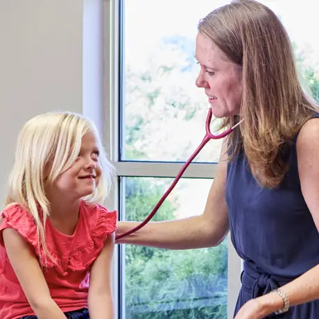 Pediatrician using a stethoscope to listen to a young female patient's heartbeat